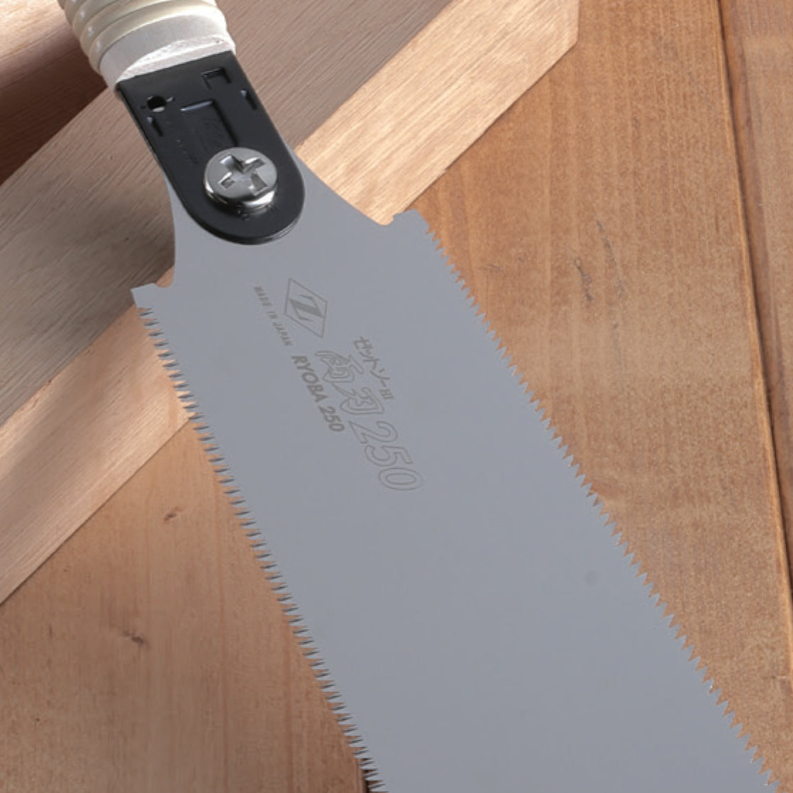 Close-up of a Zetsaw Ryoba 250 saw, shown on a wooden background.