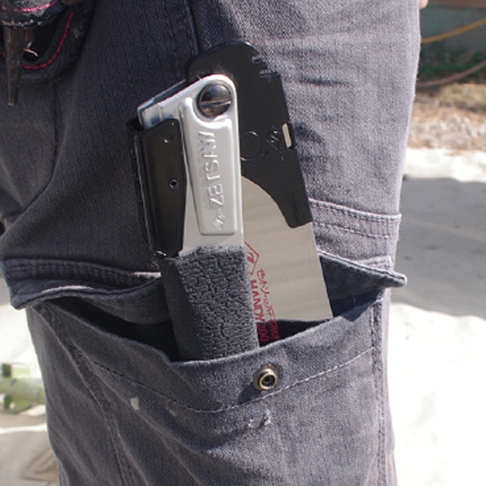 Image of the Zetsaw V Handy200 Daikume Folding Anahiki-nokogiri Japanese Saw folded and placed into the thigh pocket of a construction worker.